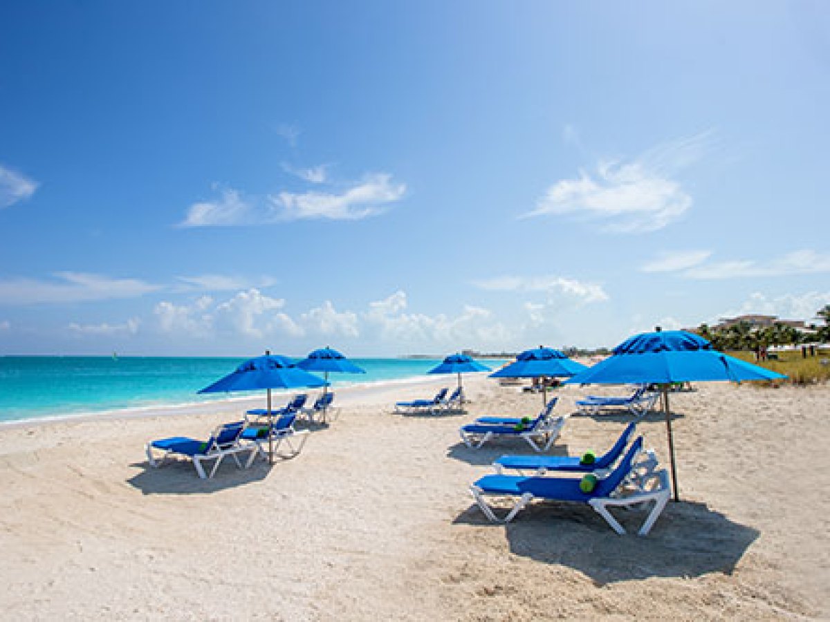 a couple of lawn chairs sitting on top of a sandy beach